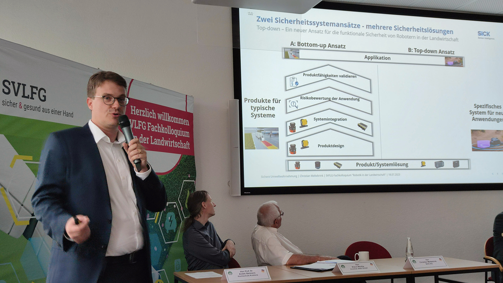 Vergrößerung des Bildes für Dr. Christian Meltebrink von der Sick AG steht vor einer Leinwand auf der seine Präsentation zu sehen ist. .