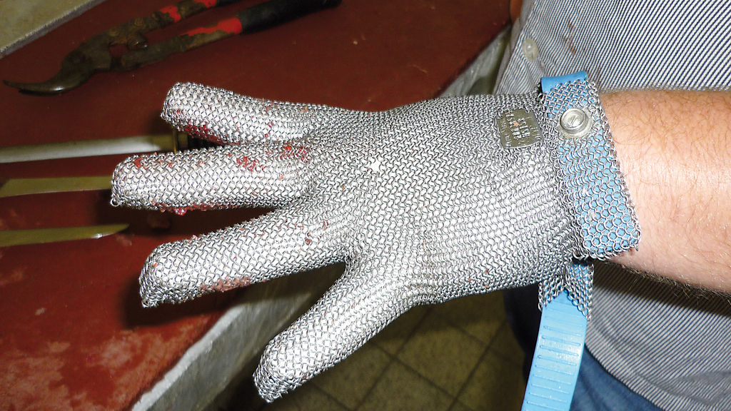 Vergrößerung des Bildes für Auf dem Bild sieht man eine Hand mit gespreizten Fingern an einem Tisch, die in einem Kettenhandschuh steckt..