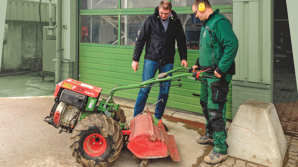 Vergrößerung des Bildes für Eine Fachkraft für Arbeitssicherheit bespricht ein Arbeitsgerät mit einem Mann in Schutzkleidung .