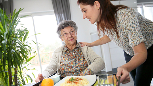 Pflegekraft mit Seniorin beim Essen