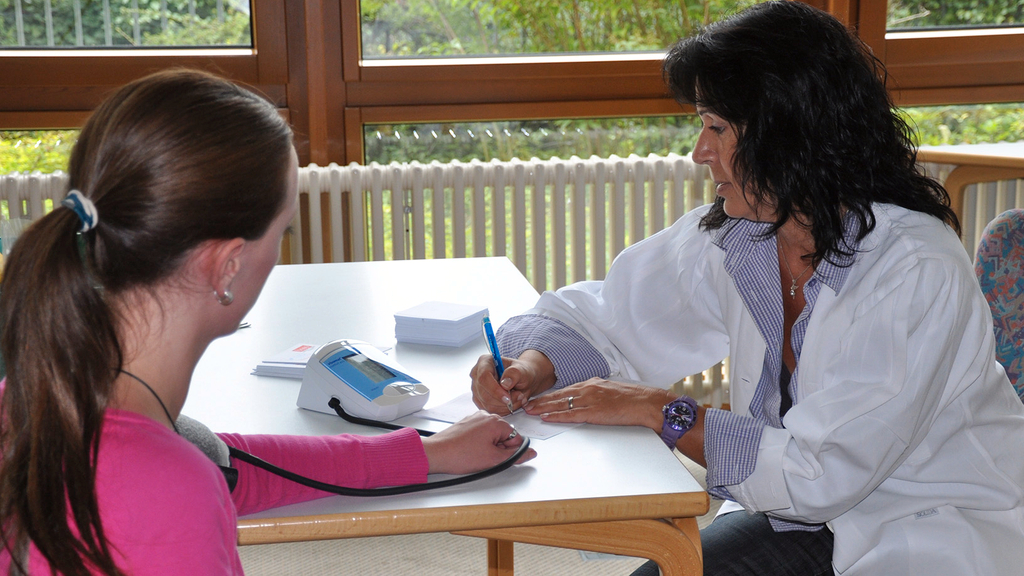 Vergrößerung des Bildes für Ärztin mit Patientin beim Blutdruckmessen.