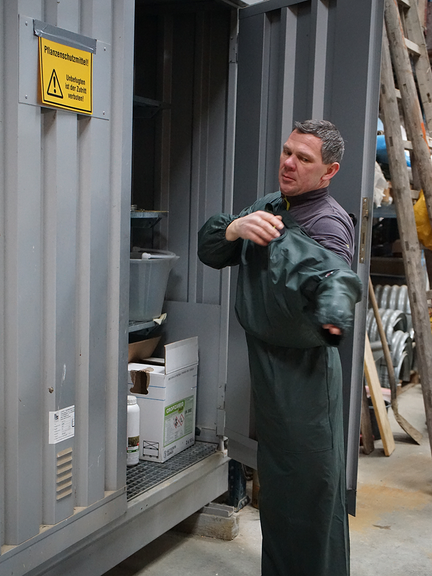 Vergrößerung des Bildes für Mann bei dem Anlegen von einer Ärmelschürze..