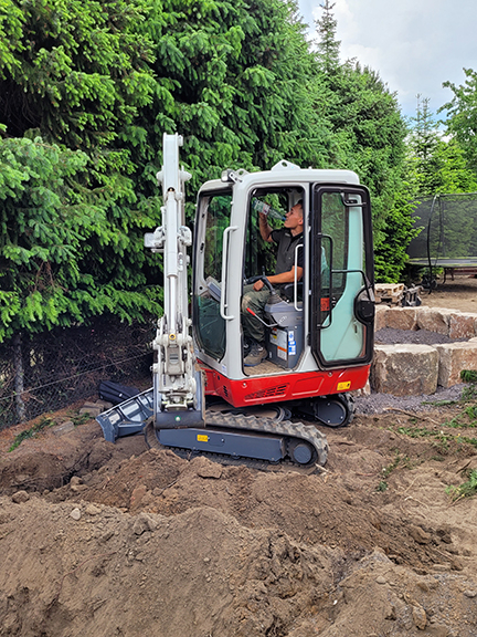 Vergrößerung des Bildes für Ein Mann sitzt in einem Bagger und trinkt aus einer Flasche Wasser.