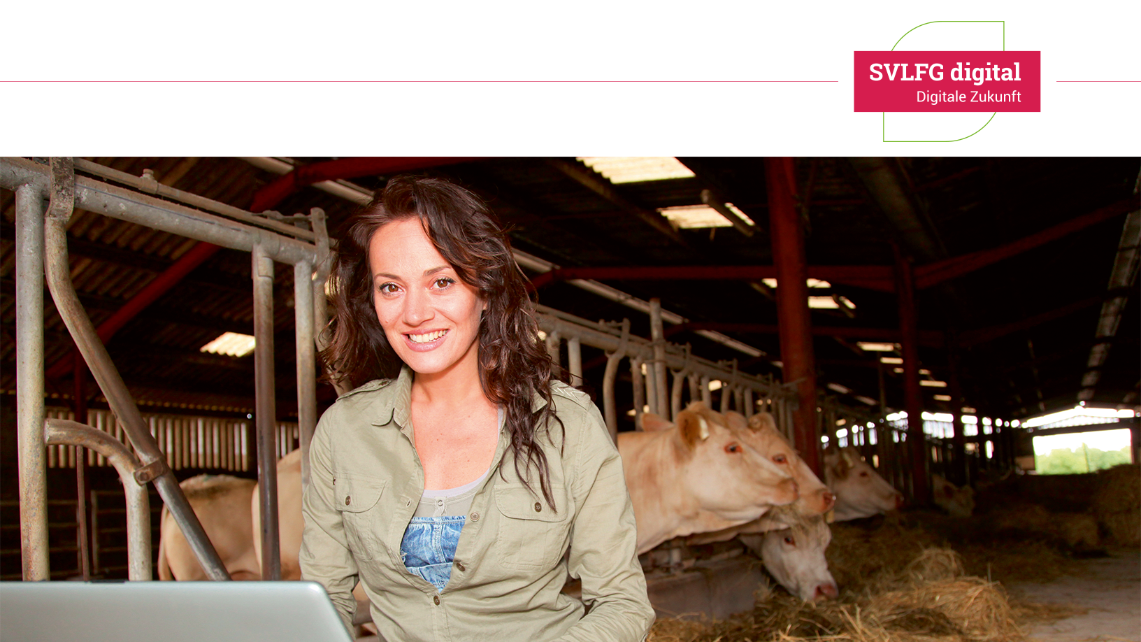 Junge Frau mit sitzt mit Laptop auf dem Schoß. Im Hintergrund ist der Rinderstall zusehen.
