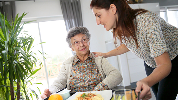 Vergrößerung des Bildes für Pflegekraft mit Seniorin beim Essen.