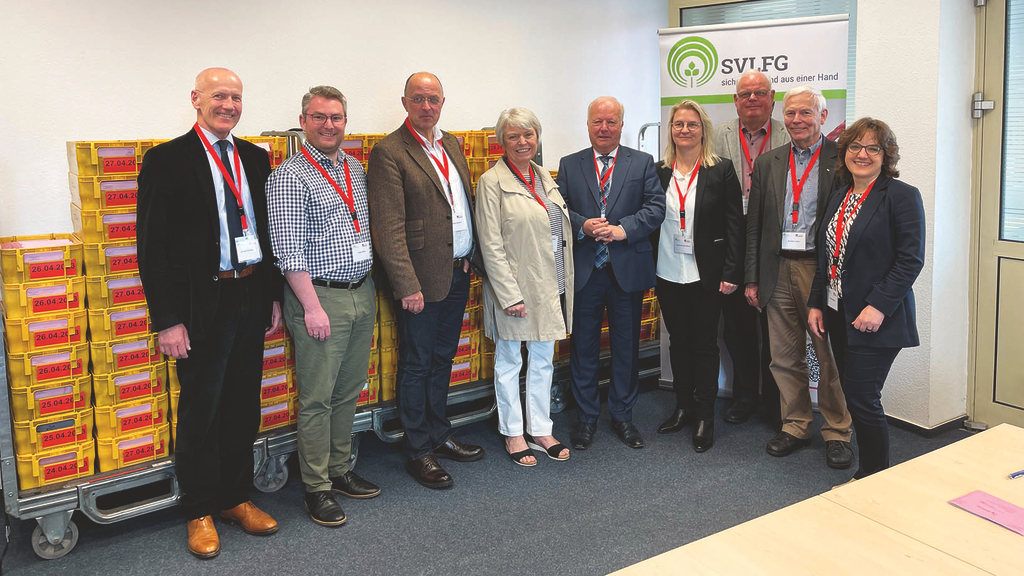 Vergrößerung des Bildes für Gruppenfoto des Wahlausschusses, im Hintergrund Rollup der SVLFG, Postkästen und Tische .