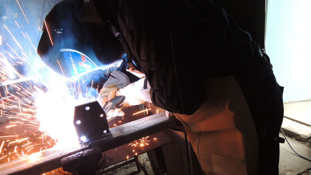 Vergrößerung des Bildes für Person in Schutzausrüstung bei Schweißarbeiten.