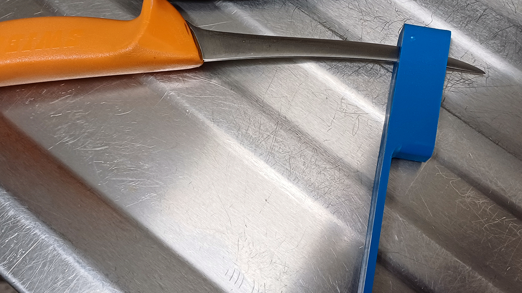 Vergrößerung des Bildes für Die Spitze eines Messers ragt aus der Öffnung der blauen Messerprüflehre heraus. Hier steht fest: Das Messer ist nicht in Ordnung..