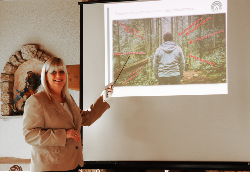Vergrößerung des Bildes für Präventionsfachfrau Petra Müller steht vor Leinwand und zeigt mit einem Stab darauf..