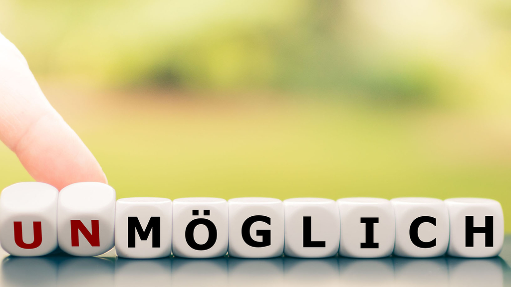 Vergrößerung des Bildes für Würfel mit dem Aufdruck Unmöglich, die Würfel mit U und N sind rot, die übrigen Würfel schwarz.