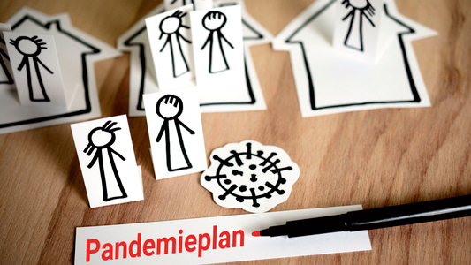 Stichmännchen, das Coronavirus und Häuser auf Papier gezeichnet auf dem Tisch liegend mit einem Stift 