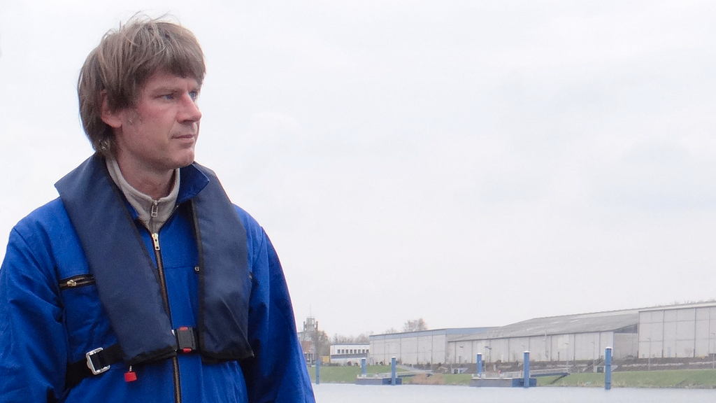 Vergrößerung des Bildes für Ein Mann steht am Wasser und trägt eine Rettungsweste.