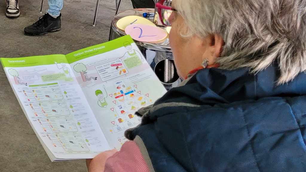 Vergrößerung des Bildes für Blick über die Schulter einer Frau, die eine Seite der Ernährungsbroschüre aufgeschlagen hat.