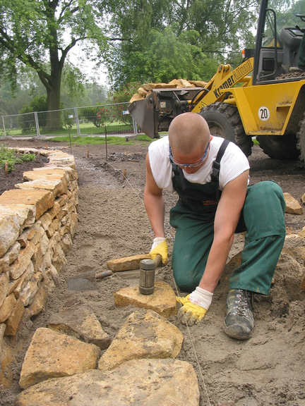 Vergrößerung des Bildes für Arbeiter beim Befestigen von Natursteinen mit einem rückschlagarmen Hammer.