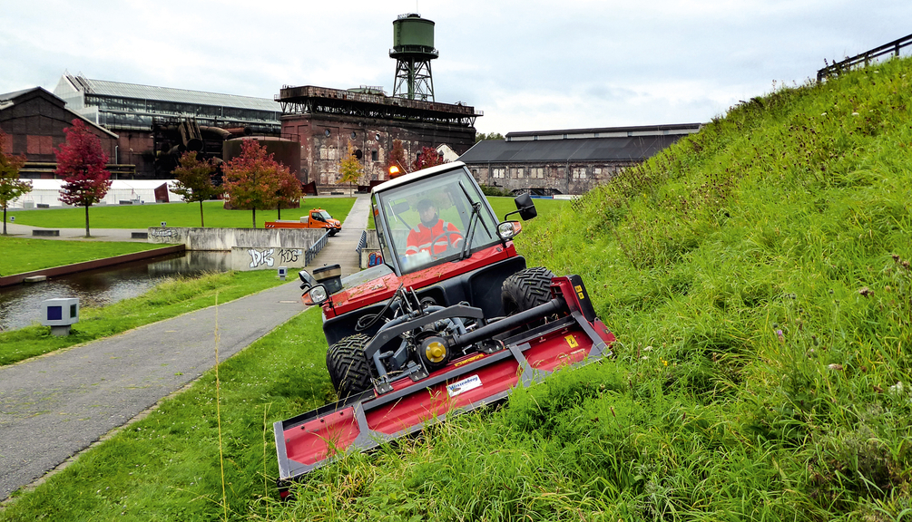 Vergrößerung des Bildes für Bild: Böschungsmäher mit Anbaumähwerk im Einsatz auf einer Böschung.