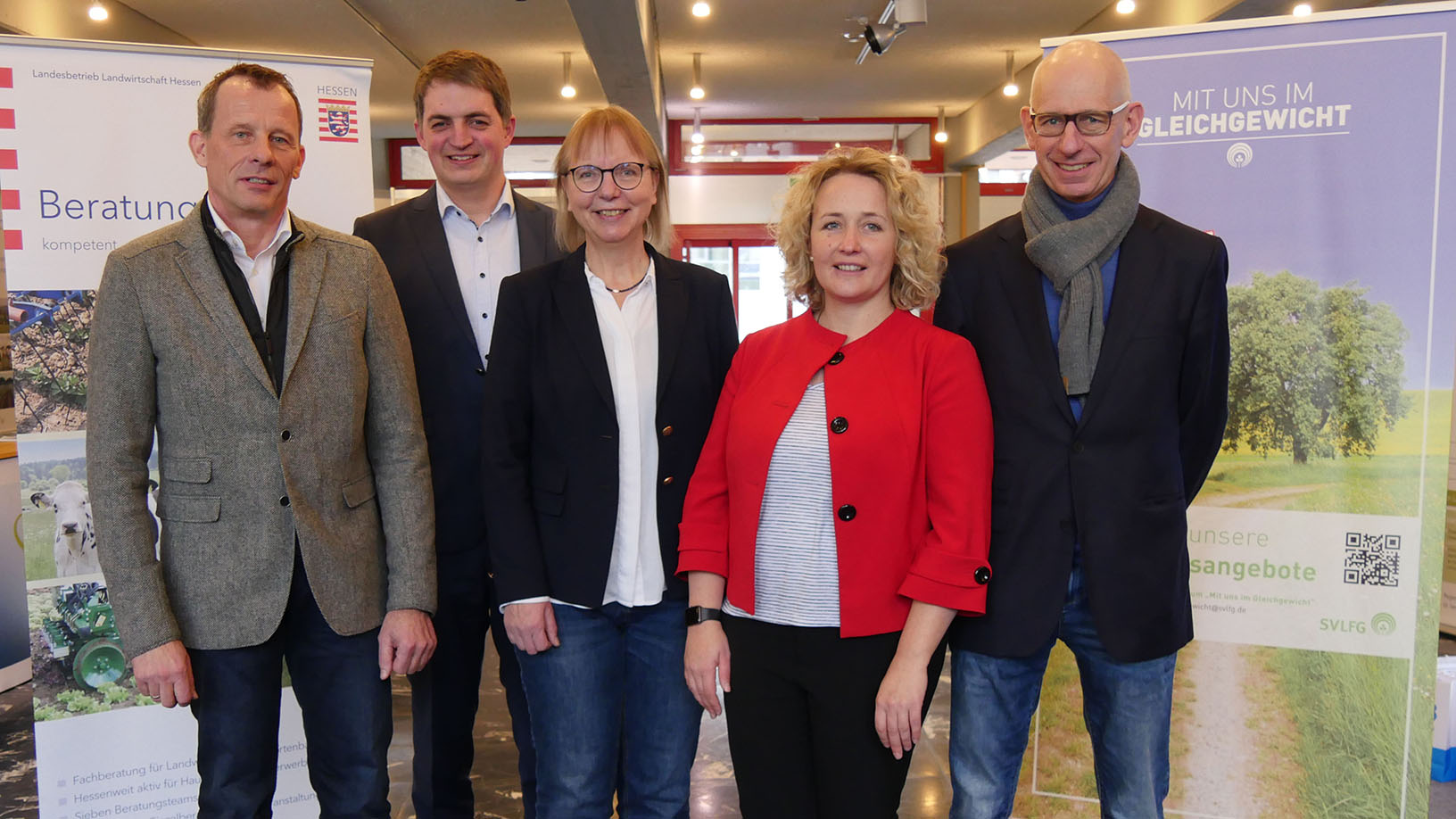 Drei Männer uns zwei Frauen stehen vor Rollups um sich vorzustellen