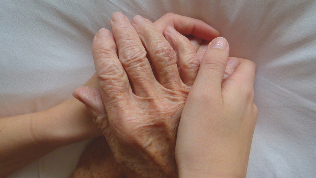 Vergrößerung des Bildes für Zwei junge Hände umarmen eine alte Hand..