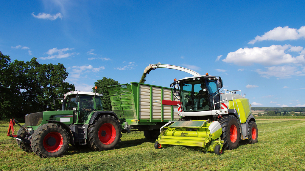 Vergrößerung des Bildes für Feldhäcksler auf dem Feld befüllt Traktor.