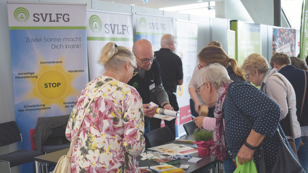 Vergrößerung des Bildes für Frauen informieren sich am Stand der SVLFG. Flipcharts sind am Beratungsstand aufgebaut und Informationsmaterial wird durch die Mitarbeitetenden der SVLFG vorgestellt.