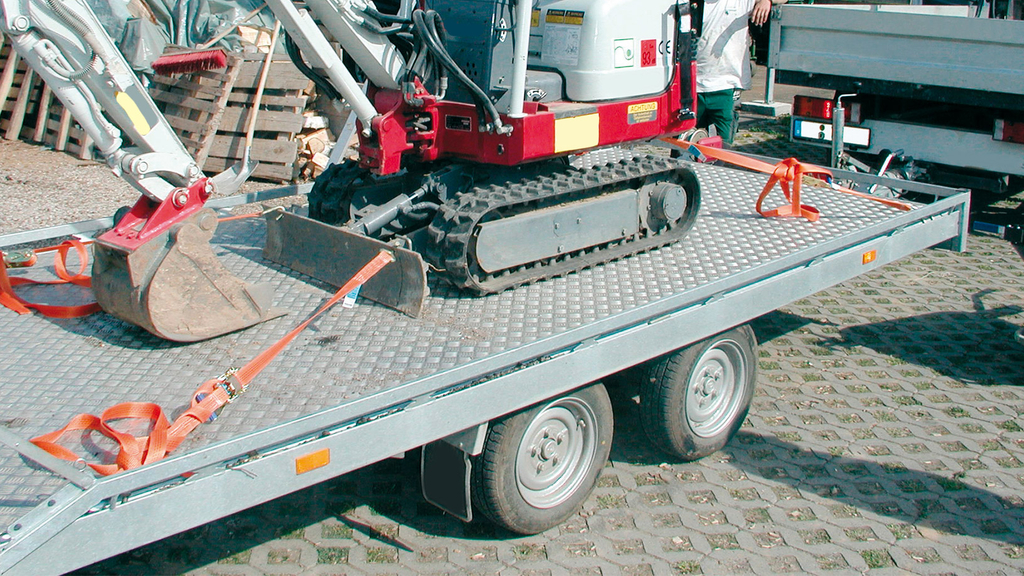 Vergrößerung des Bildes für Auf einer Ladefläche mit zwei Rädern ist mittig mit orangefarbenen Seilen ein Minibagger gesichert..